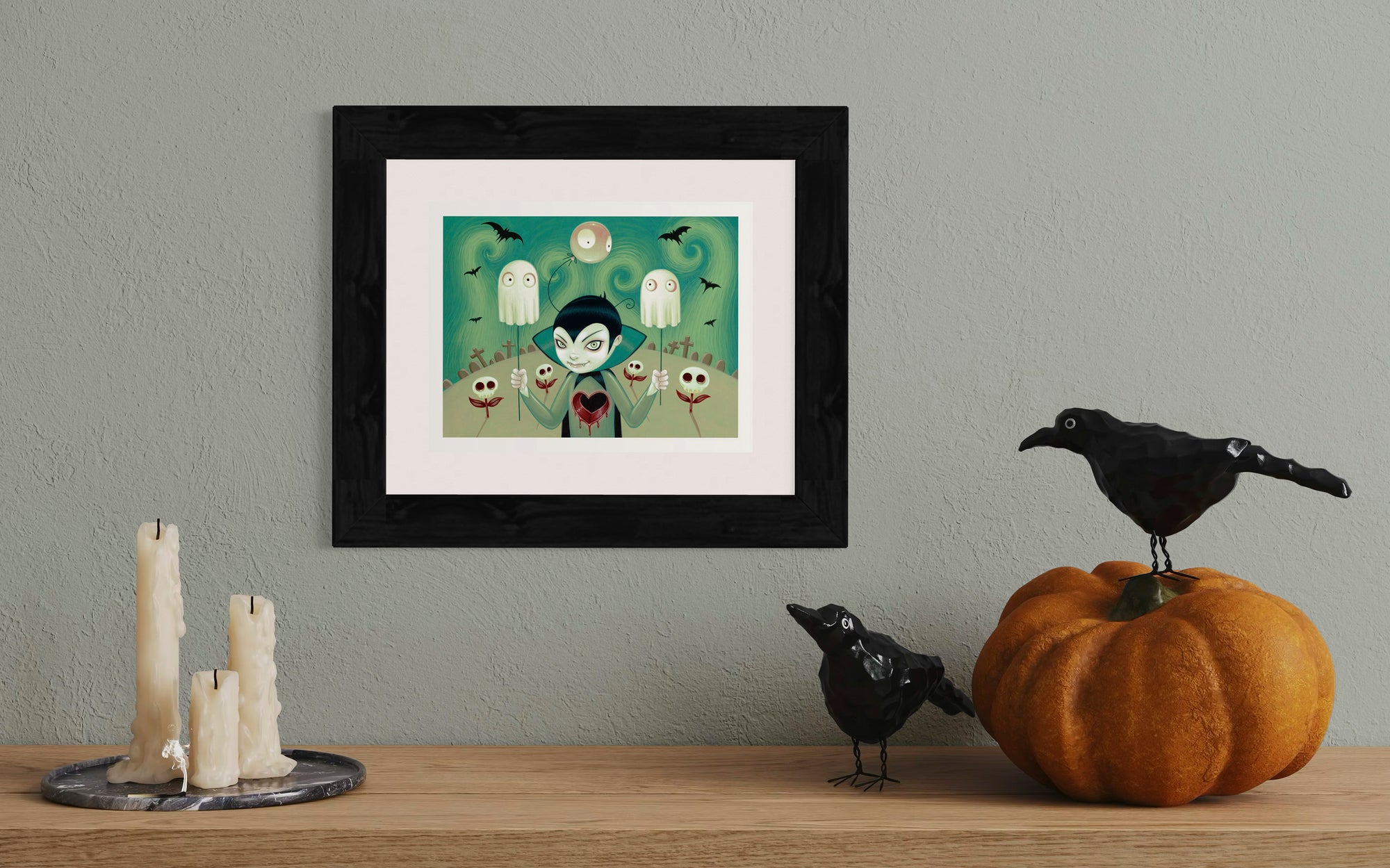 Framed Halloween-themed artwork on a wall with decorative items below.