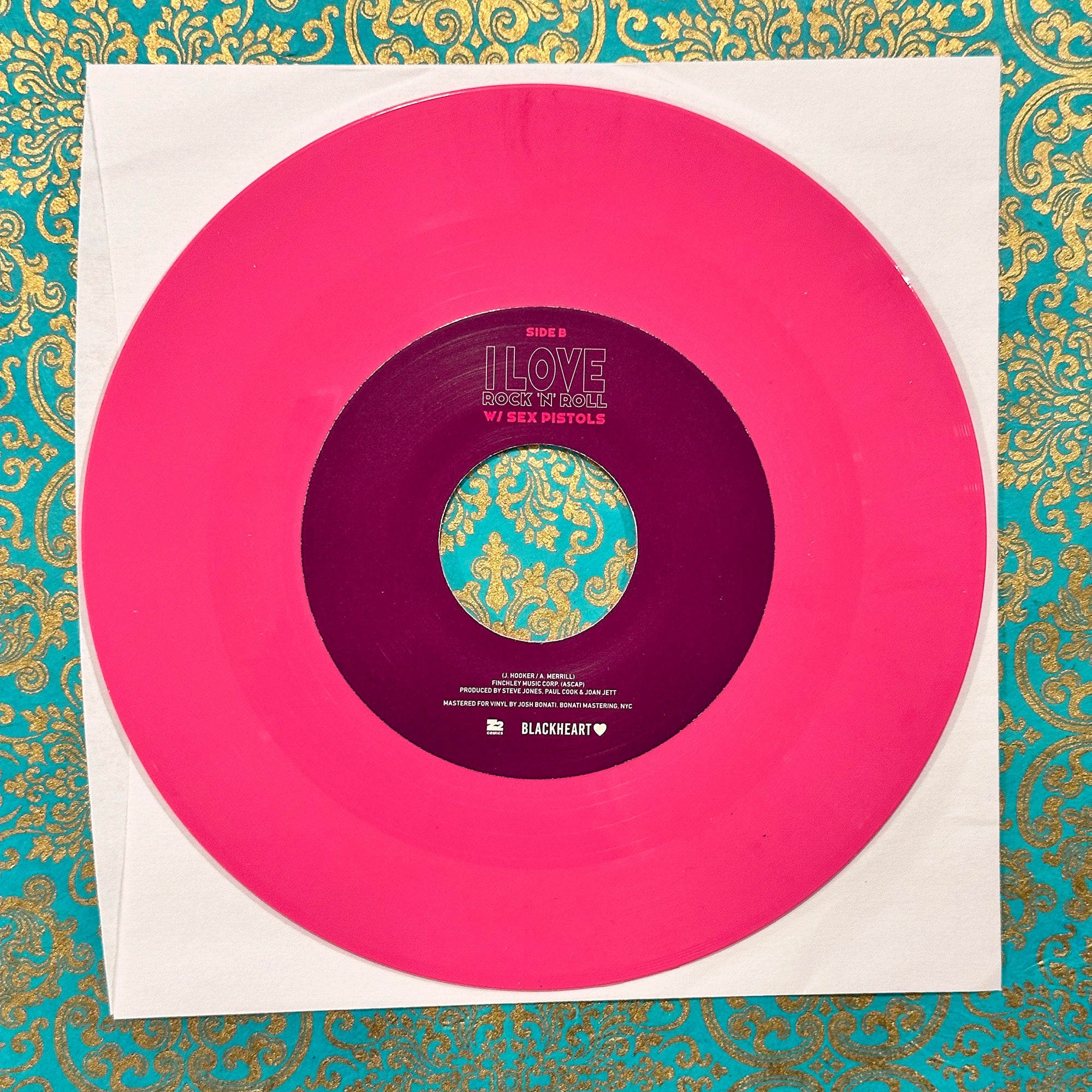 Vinyl record with a pink outer sleeve and purple inner label on a decorative background