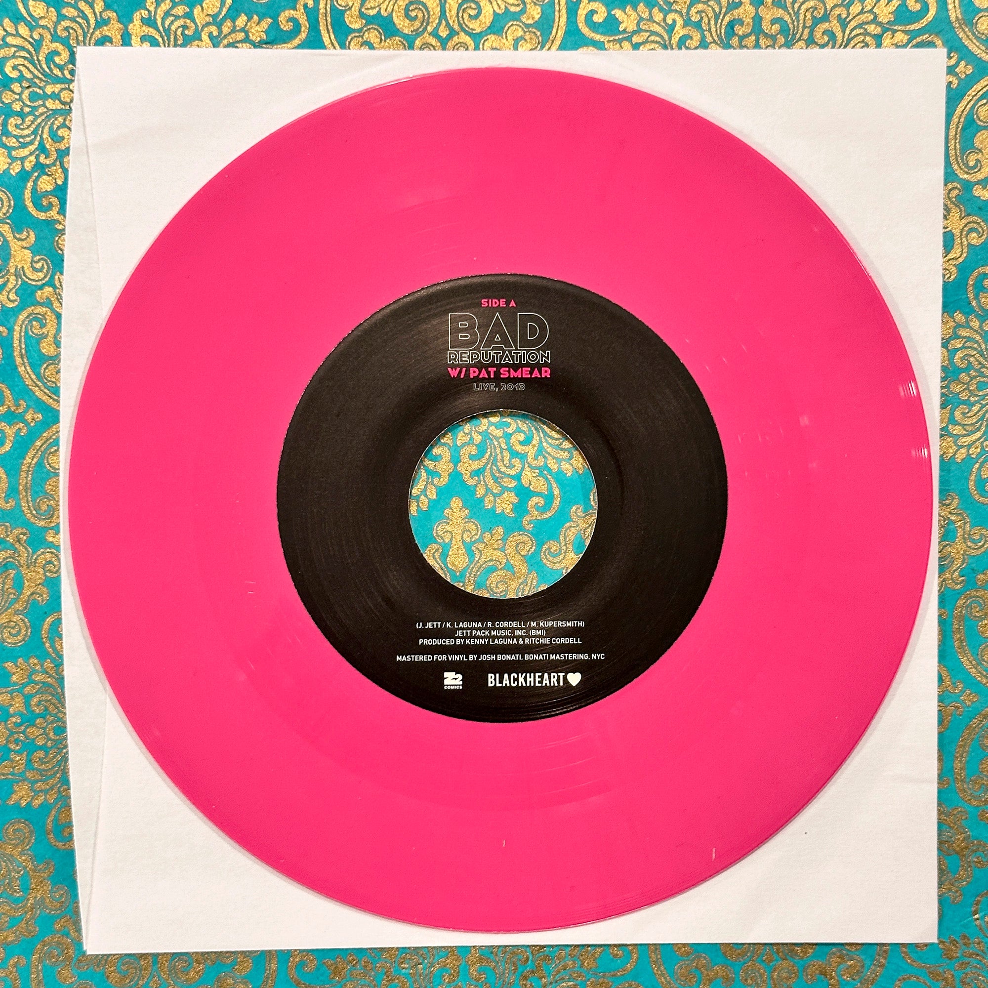 Vinyl record with a pink outer sleeve on a decorative background